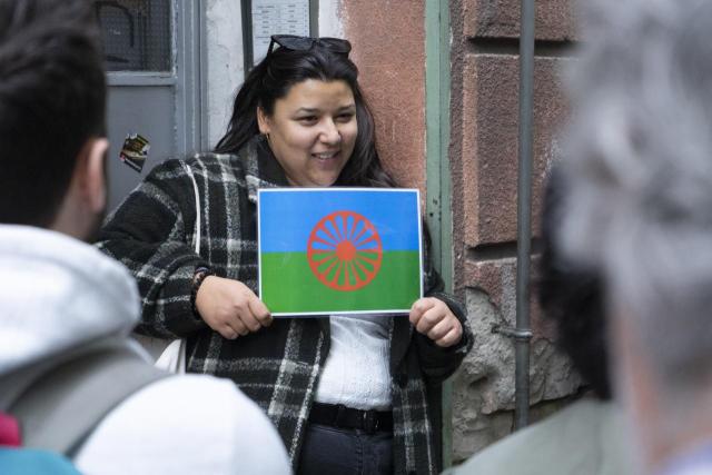 a woman standing holding a romani flag