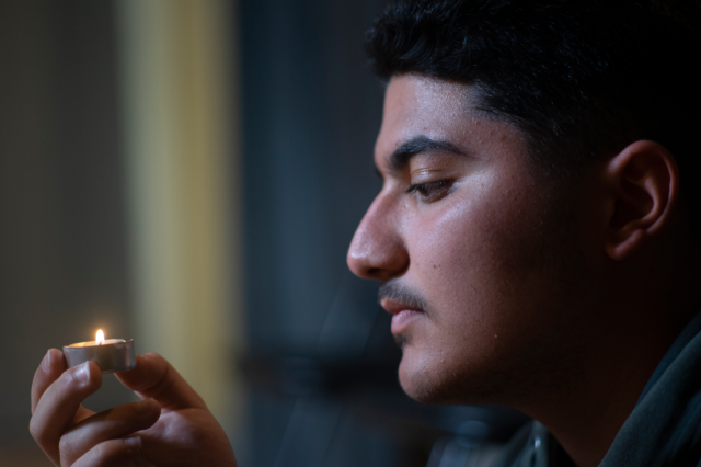 a young male holding a small candle in hands