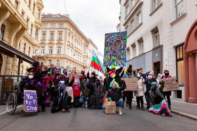 A group of people wearing colourful masks standing on the street 