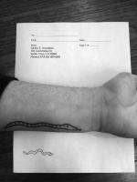 An arm with a snake tattoo poses in top of a sheet of paper with Gloria E. Anzaldúa Name and address, there is also a snack drawer in the paper.