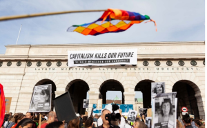 on Top of a Facade we read "Capitalism kills our future" and a Andean colourful flag